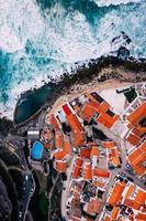 Aerial view of Azenhas do mar from top, view of the red rooftop of a small town along Portuguese coastline facing the Atlantic Ocean, Colares, Portugal. photo