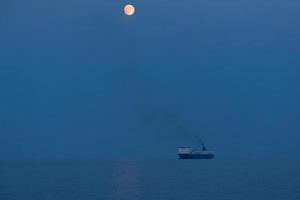 proa del barco al atardecer luna llena foto