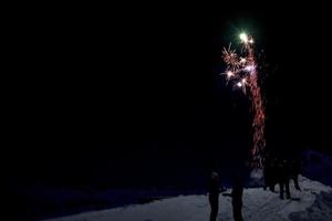 feliz año nuevo y feliz navidad fuegos artificiales sobre fondo de nieve de montaña foto