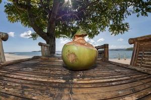 fresh coconut on bamboo table on the beach photo