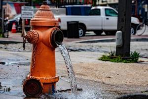 Street orange hydrant spreading water on the street photo