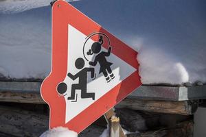 niños jugando al signo de advertencia en la nieve foto