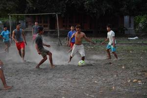 gili asahan, indonesia - 22 de agosto de 2016 - los niños juegan al fútbol al atardecer en un campo de palmeras cerca de la playa foto