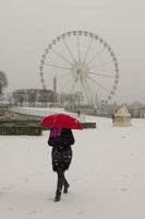 Paris under snow in winter time a girl walking with a red umbrella near Concorde place photo