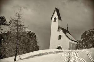 vista de la iglesia de dolomitas en tiempo de nieve de invierno en blanco y negro foto