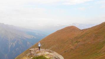 racha, Georgië, 2022 - antenne vlieg over- visie sportief vrouw solo Aan klif gezichtspunt kijk maar Kaukasus bergen in racha, Georgisch regio. udziro meer wandelen spoor video