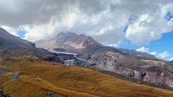 Alti Hut with the view of Mount Kazbeg in Caucasus, Georgia. There slopes are barren and stony below the snow-capped peak and the Gergeti Glacier. Tranquility and Love mountains video