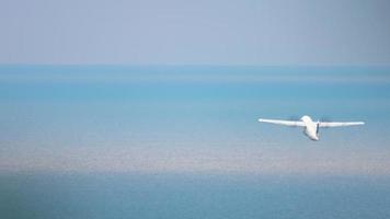 los aviones turbohélice suben después del despegue sobre el mar. tiro largo de un avión de pasajeros que se va volando video