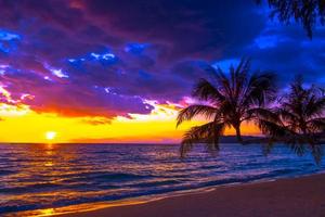 hermosa puesta de sol sobre el mar en la playa tropical con palmeras y cielo colorido para viajes y vacaciones foto