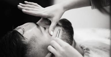 Barber shaves the bearded man photo