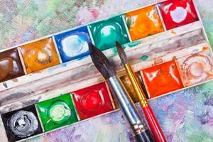 watercolor set and brushes on oil picture background photo