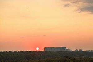 low red sun above horizon during sunrise over city photo