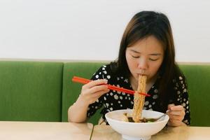 mujer asiática disfruta comiendo fideos en el restaurante foto