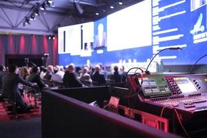 London, UK, 2019 - Technician handling the lights at a conference with an anonymized blurry audience and stage in the background photo