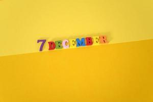 December 7 on yellow and paper background with wooden and multicolored letters with space for text. photo