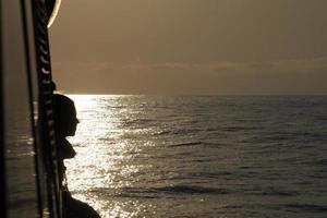 silueta de niña en un barco al atardecer foto