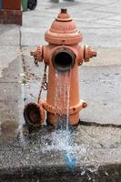Street orange hydrant spreading water on the street photo
