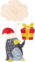 cartoon penguin with christmas present and thought bubble in retro textured style vector