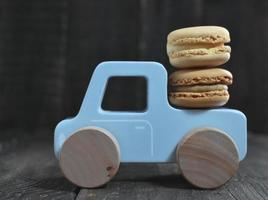 macarons dulces en coche de juguete de madera foto