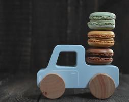 macarons dulces en coche de juguete de madera foto