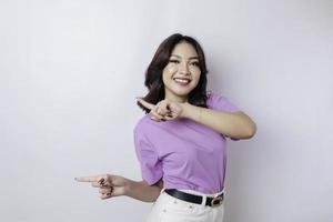 Smiling beautiful Asian woman pointing finger to empty space beside her isolated white background photo