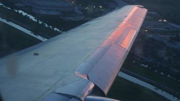 Verkehrsflugzeug, das in den Strahlen des Sonnenuntergangs oder der Morgendämmerung abhebt, Blick aus der ersten Person aus dem Flugzeugfenster. pov auf die stadt von einem flugzeug, das abhebt video