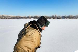 Lonely old hermit man, in winter crosses the river on ice photo