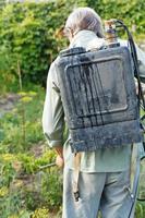 worker spraying of pesticide on country garden photo