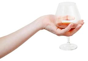 hand holds glass goblet with cognac isolated photo