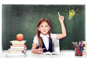 Young cute girl at chalkboard with light bulb over head photo