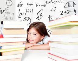 Young cute girl sitting at the table and reading a book photo