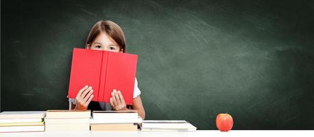 linda jovencita sentada en la mesa y leyendo un libro foto