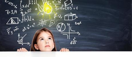 Young cute girl at chalkboard with light bulb over head photo