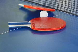 dos paletas, pelota de tenis en una mesa de ping pong azul foto