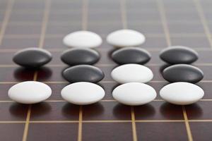 piedras durante el juego go jugando en una tabla de madera foto