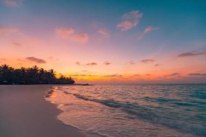 playa de la isla del atardecer. playa del paisaje del paraíso. cielo de arena de mar de naturaleza tropical con silueta de bosque de palmeras y relajantes olas de agua del océano. hermosa playa de viaje, amanecer sobre destino de vacaciones foto