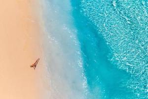 vista aérea de una mujer en la playa en bikini tumbada y tomando el sol. olas perfectas, chapoteo relajante verano libertad estilo de vida de lujo