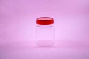 red lid plastic jar isolated on a pink photo