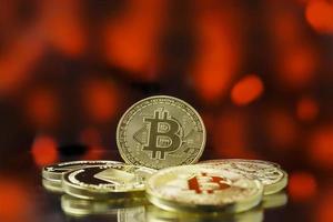 Stack of gold bitcoin coins with red bokeh background, bearish market photo