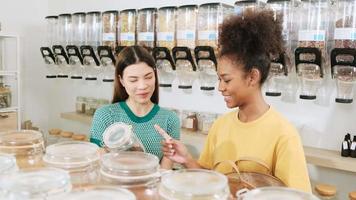 två ung kvinna kunder är välja och handla för organisk Produkter i påfyllning Lagra med återanvändbar påsar, noll-avfall livsmedelsbutik, och plastfri, eco miljövänlig, hållbar livsstilar. video