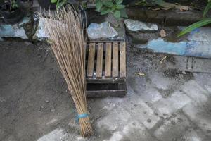 Broom sticks and a small seat made of bamboo with a road