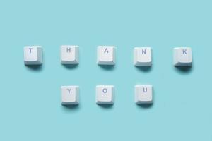 Word THANK YOU written on computer keyboard keys isolated on a turquoise photo