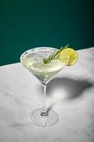 Martini cocktail with ice and slice of lime on marble table background. Alcoholic cocktail or non-alcoholic mocktail. photo