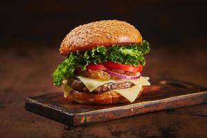 hamburguesa casera con mermelada de carne, queso y cebolla en una tabla de madera. concepto de comida rápida, comida americana foto