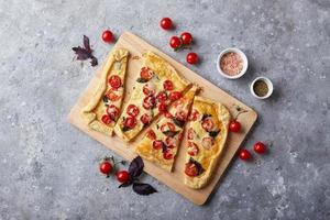 Puff pastry tart with cherry tomatoes, mozzarella and purple basil photo