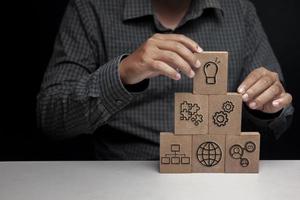 Hand stacked wooden blocks stacked with business icons for online corporate custody management concept. photo