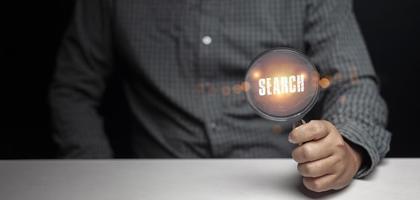 business man's hand holding a magnifying glass with text search photo