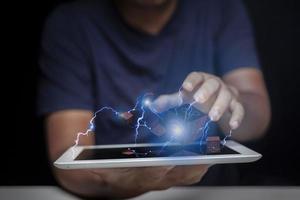 Man holding a tablet in his palm and showing off his creativity and speed of internet communication through square balls and lightning, creative ideas through high speed internet. photo