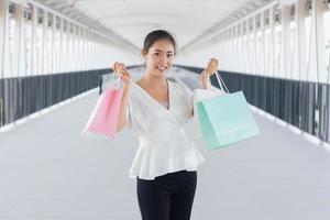 Portrait of happy smiling woman with shopping bags in corridor walk way. Beautiful woman with a paper bag. photo