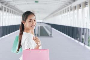 Portrait of happy smiling woman with shopping bags in corridor walk way. Beautiful woman with a paper bag. photo